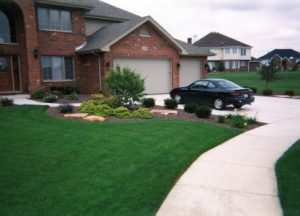 large lawn with flowerbed in front of a brick house