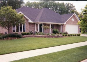 large lawn with retaining wall in front of a brick house