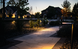 Paver pathway with flower beds lit with outdoor lighting design