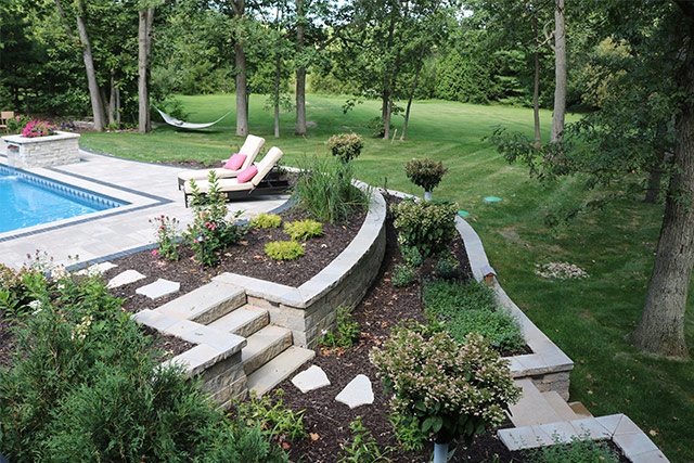 landscaping, flowerbeds, paver stairs and pathway leading to pool area